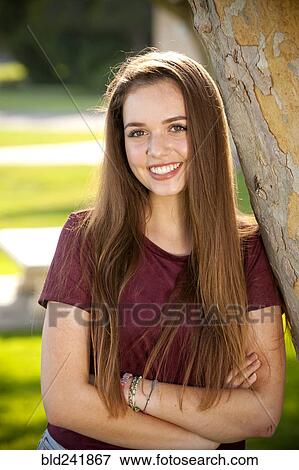 Portrait of smiling Caucasian teenage girl leaning on tree View Large Photo Image Stock Photo - Portrait of smiling Caucasian teenage girl leaning on tree. Fotosearch