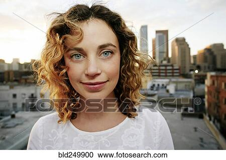 Stock Image - Portrait of smiling Caucasian woman on urban rooftop. Fotosearch