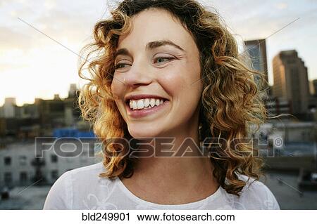 Stock Image - Portrait of smiling Caucasian woman on urban rooftop. Fotosearch