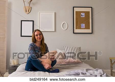 Portrait of smiling Caucasian woman sitting on bed View Large Photo Image Picture - Portrait of smiling Caucasian woman sitting on bed. Fotosearch