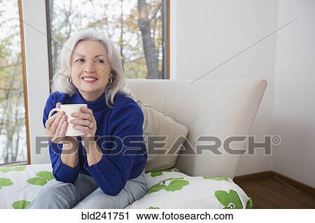 Stock Image - Portrait of smiling Caucasian woman drinking coffee. Fotosearch