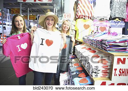 Stock Image - Portrait of smiling Caucasian woman showing t-shirts. Fotosearch