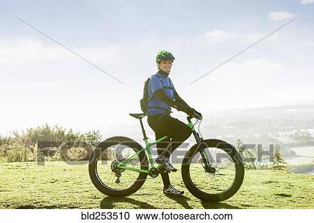 Stock Image - Portrait of smiling Caucasian woman riding bicycle. Fotosearch