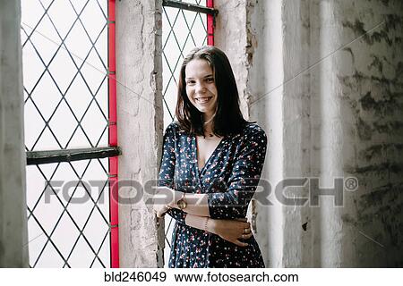 Portrait of smiling Caucasian woman standing near window View Large Photo Image Stock Photo - Portrait of smiling Caucasian woman standing near window. Fotosearch