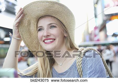 Stock Photography - Portrait of smiling Caucasian woman wearing hat in city. Fotosearch