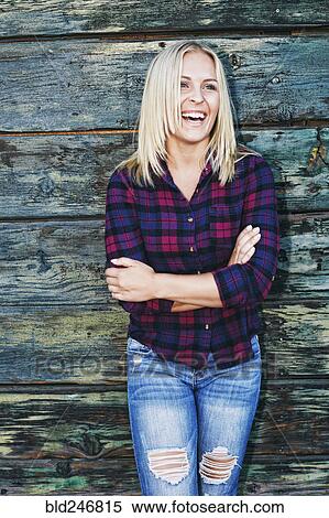 Stock Photography - Portrait of smiling Caucasian woman leaning on wooden wall. Fotosearch