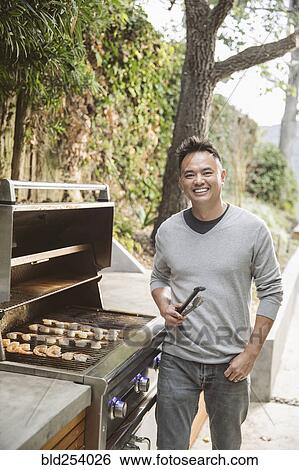 Portrait of smiling Chinese man cooking on grille View Large Photo Image Stock Photograph - Portrait of smiling Chinese man cooking on grille. Fotosearch