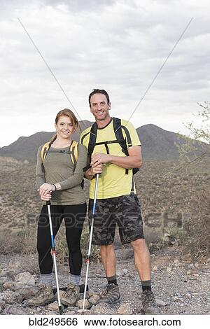 Stock Photograph - Portrait of smiling couple hiking in desert. Fotosearch