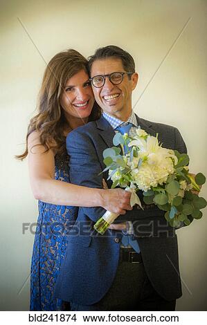 Picture - Portrait of smiling couple holding bouquet of flowers. Fotosearch