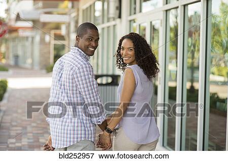 Portrait of smiling couple holding hands and looking at camera View Large Photo Image Stock Photo - Portrait of smiling couple holding hands and looking at camera. Fotosearch