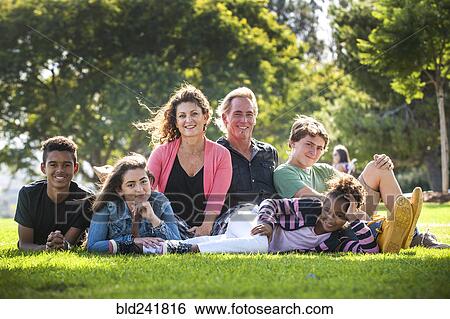 Stock Photograph - Portrait of smiling family on grass in park. Fotosearch