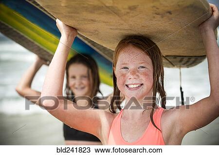 Portrait of smiling girls balancing surfboards on top of heads View Large Photo Image Stock Image - Portrait of smiling girls balancing surfboards on top of heads. Fotosearch