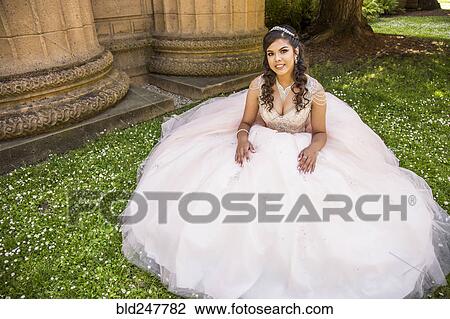 Stock Image - Portrait of smiling Hispanic girl wearing gown. Fotosearch