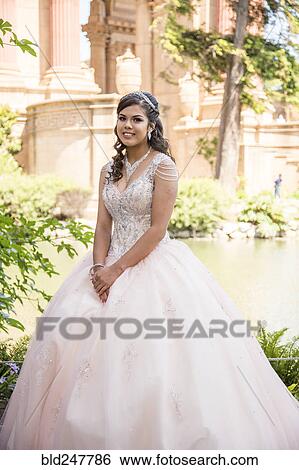 Stock Photograph - Portrait of smiling Hispanic girl wearing gown. Fotosearch