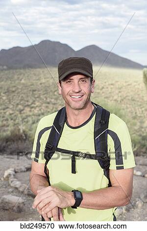 Stock Image - Portrait of smiling Hispanic man hiking in desert. Fotosearch