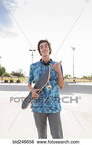 Stock Photo - Portrait of smiling Hispanic man holding skateboard. Fotosearch
