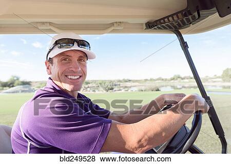 Stock Photo - Portrait of smiling Hispanic man driving golf cart. Fotosearch