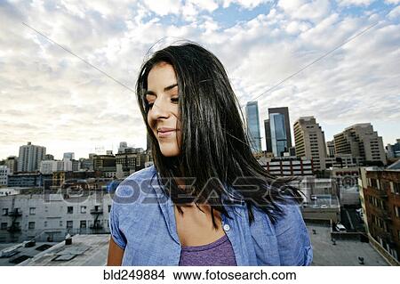 Picture - Portrait of smiling Hispanic woman on urban rooftop. Fotosearch