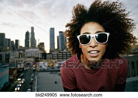 Stock Photography - Portrait of smiling Hispanic woman on urban rooftop. Fotosearch