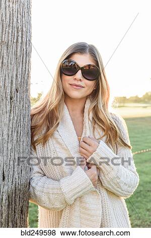 Portrait of smiling Hispanic woman wearing sunglasses leaning on tree View Large Photo Image Stock Photo - Portrait of smiling Hispanic woman wearing sunglasses leaning on tree. Fotosearch