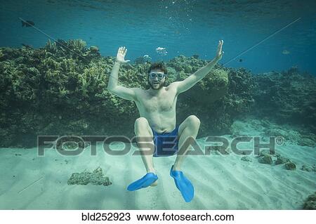 Stock Image - Portrait of smiling man swimming underwater in ocean. Fotosearch