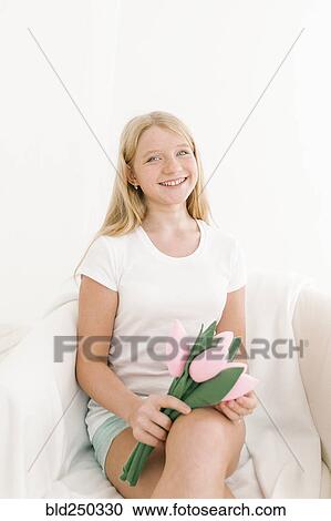 Stock Image - Portrait of smiling Middle Eastern girl holding toy flowers. Fotosearch