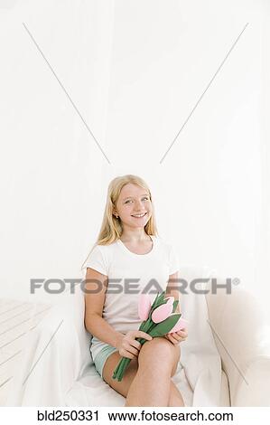 Stock Image - Portrait of smiling Middle Eastern girl holding toy flowers. Fotosearch