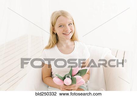 Stock Image - Portrait of smiling Middle Eastern girl holding toy flowers. Fotosearch