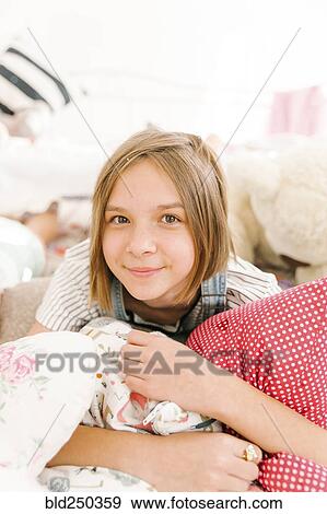 Stock Photo - Portrait of smiling Middle Eastern girl holding pillows. Fotosearch