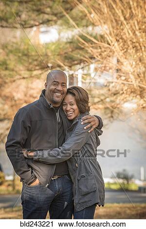 Stock Image - Portrait of smiling Mixed Race father and daughter hugging outdoors. Fotosearch