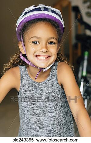 Stock Photography - Portrait of smiling Mixed Race girl wearing helmet. Fotosearch