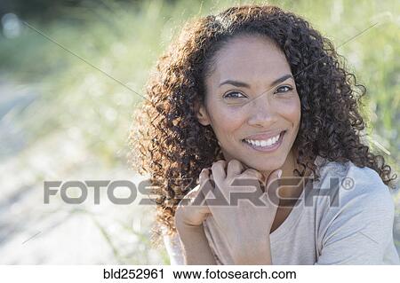 Stock Image - Portrait of smiling Mixed Race woman at beach. Fotosearch