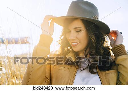 Portrait of smiling Mixed Race woman adjusting hat View Large Photo Image Stock Image - Portrait of smiling Mixed Race woman adjusting hat. Fotosearch