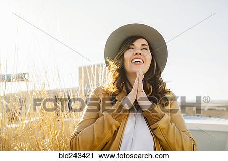 Stock Image - Portrait of smiling Mixed Race woman praying. Fotosearch