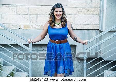 Stock Image - Portrait of smiling Mixed Race woman leaning on staircase railings. Fotosearch