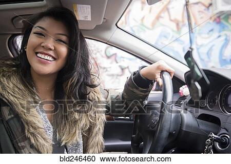 Stock Image - Portrait of smiling Mixed Race woman driving car. Fotosearch