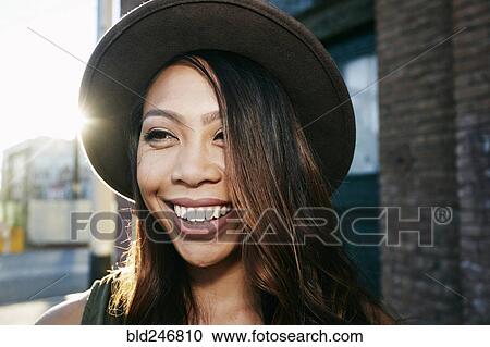 Stock Image - Portrait of smiling Mixed Race woman posing in city. Fotosearch