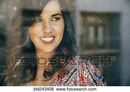 Stock Photo - Portrait of smiling Mixed Race woman behind window. Fotosearch