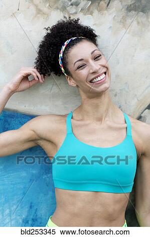 Stock Photography - Portrait of smiling Mixed Race woman leaning on wall. Fotosearch