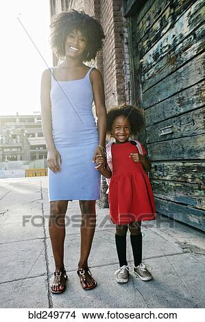 Picture - Portrait of smiling mother and daughter standing on sidewalk. Fotosearch