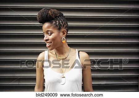Stock Photo - Portrait of smiling of African American woman with braids near metal wall. Fotosearch
