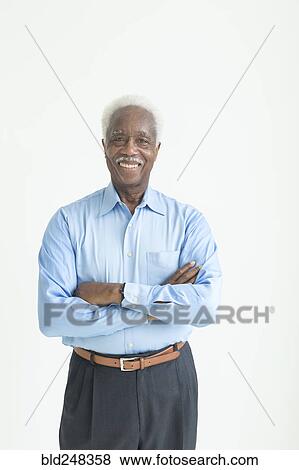 Stock Photo - Portrait of smiling older Black man with arms crossed. Fotosearch