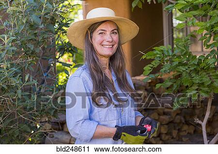 Stock Image - Portrait of smiling older Caucasian woman in the garden. Fotosearch