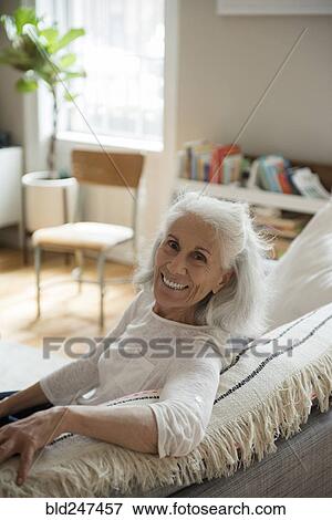 Stock Photo - Portrait of smiling older woman on sofa. Fotosearch