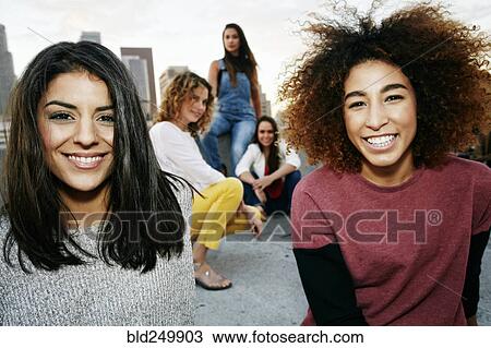 Stock Image - Portrait of smiling women on urban rooftop. Fotosearch