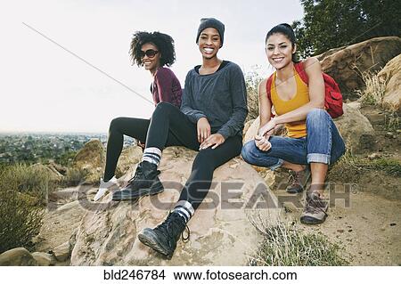 Picture - Portrait of smiling women sitting on rock. Fotosearch