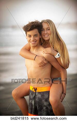 Stock Photography - Portrait of teenage boy carrying teenage girl piggyback. Fotosearch