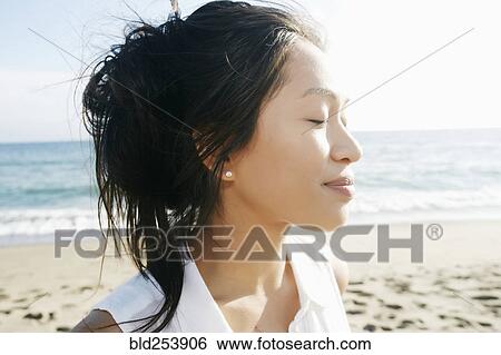 Stock Photograph - Portrait of Vietnamese woman at beach with eyes closed. Fotosearch