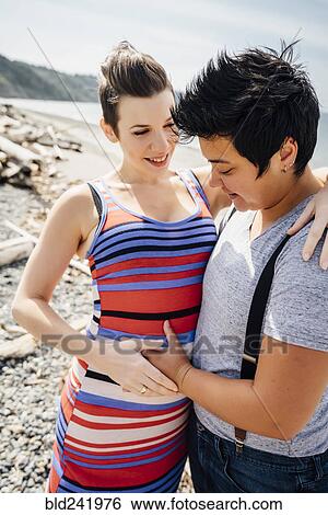 Pregnant lesbian couple hugging on beach View Large Photo Image Stock Photograph - Pregnant lesbian couple hugging on beach. Fotosearch