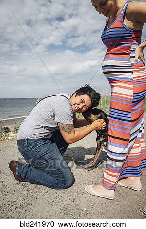 Pregnant lesbian couple playing with dog at waterfront View Large Photo Image Stock Image - Pregnant lesbian couple playing with dog at waterfront. Fotosearch